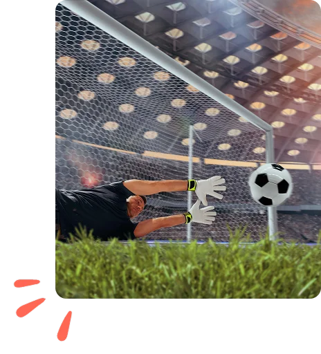 Dans un stade illuminé, un gardien de but en tenue noire plonge pour repousser un ballon qui file vers le but. La scène est empreinte d'action et de détermination.